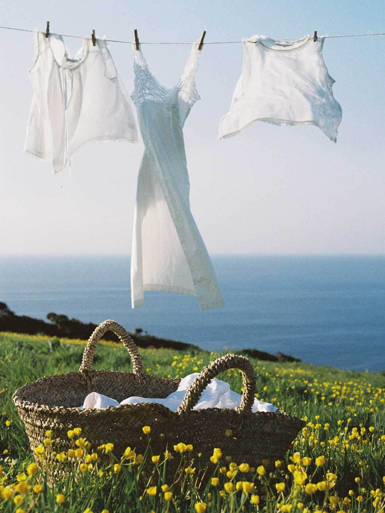 Large beldi basket being used to hang white linen out to dry on a washing line by the sea