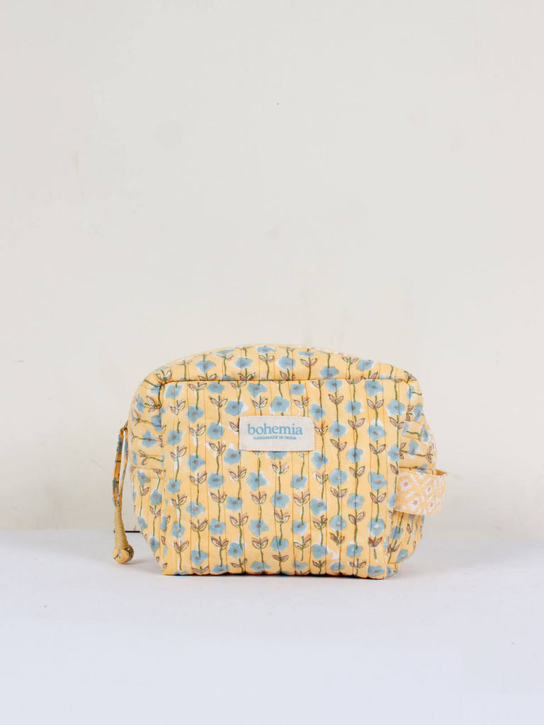 A quilted Garland washbag with buttrermilk yellow and light blue ditsy floral block print pattern