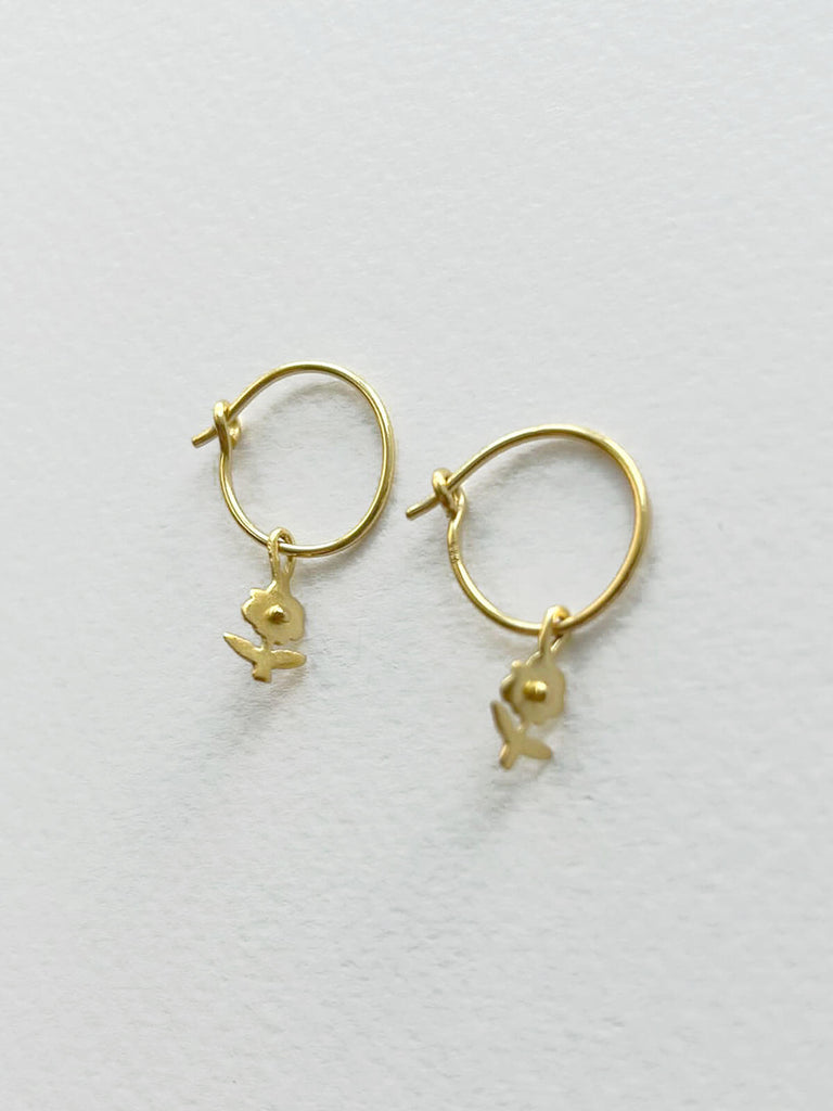 Delicate handmade gold hoop earrings for wholesale featuring a pretty daisy charm