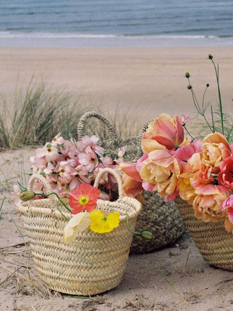 Flower filled handwoven Market Baskets on a sandy beach