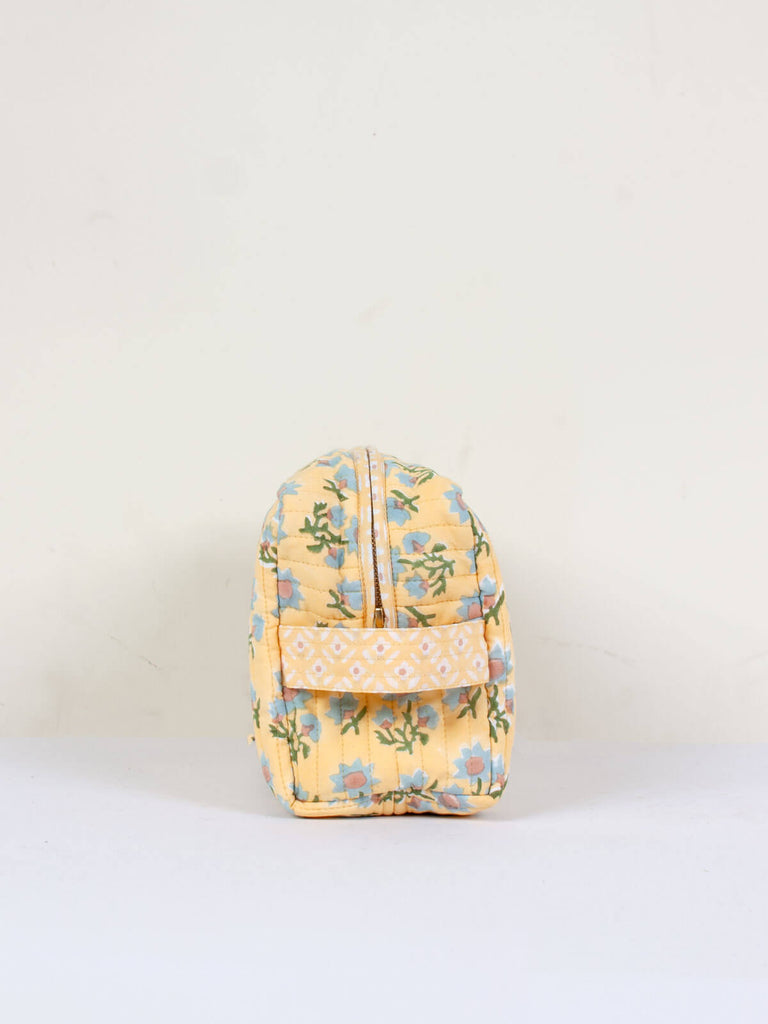 The practical carry handle on the side of a buttermilk yellow quilted Posie washbag