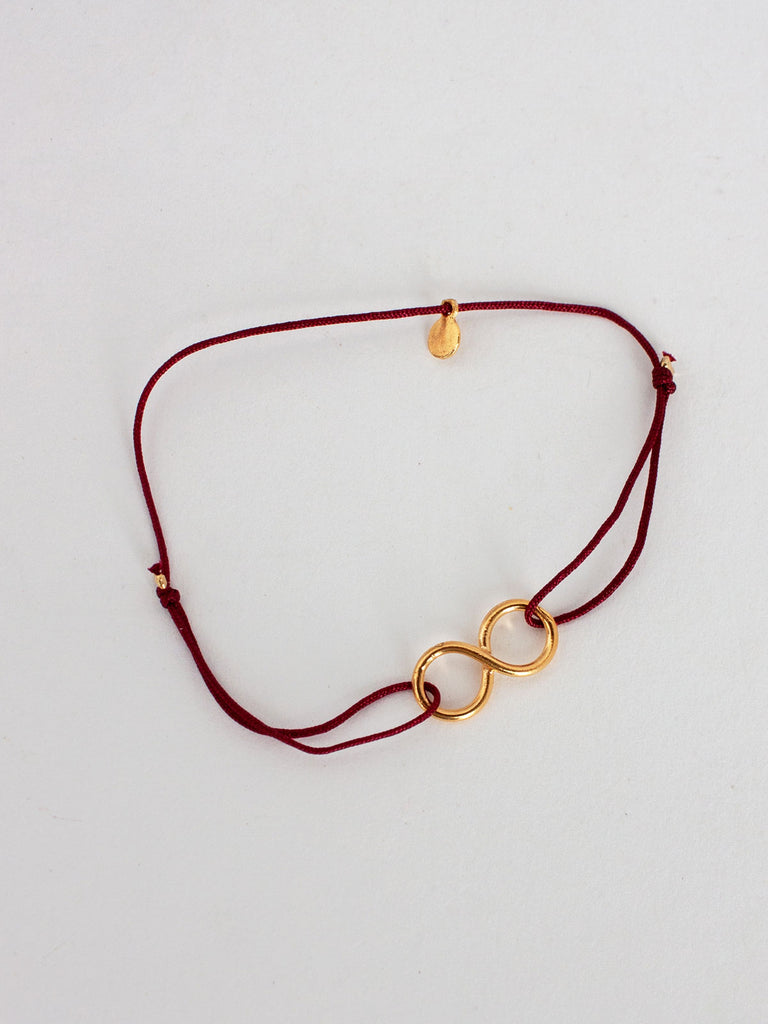 Gold infinity bracelet with deep red silk thread by Bohemia Design
