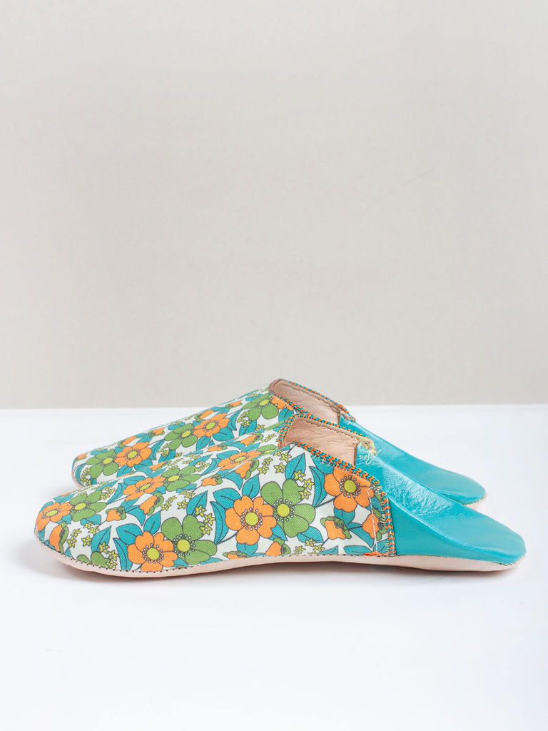 A pair of Moroccan babouche slippers in an aqua and orange floral pattern by Bohemia Design