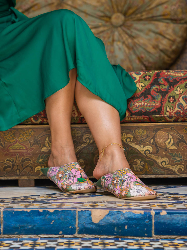 Woman wearing A pair of Moroccan babouche slippers in an olive and pink floral pattern by Bohemia Design