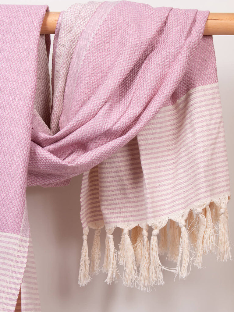 Striped Amalfi Hammam Towel in vintage pink stripe by Bohemia Design hanging on a wooden rod