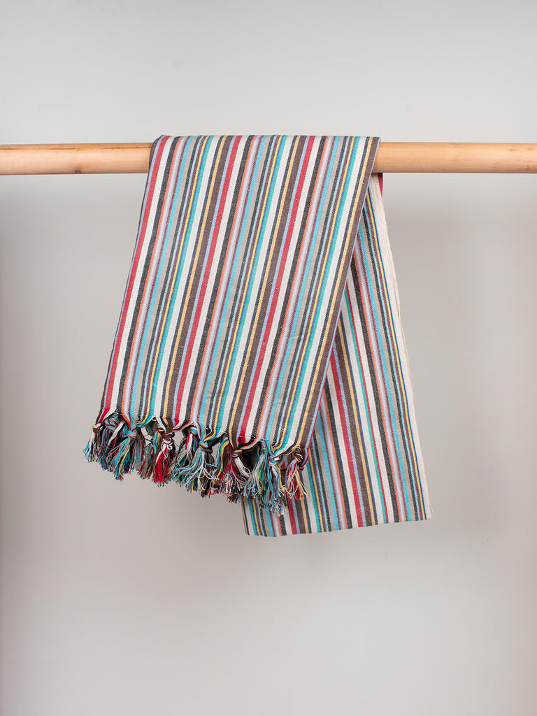 Hammam towel in rainbow stripe pattern hanging on a wooden rod