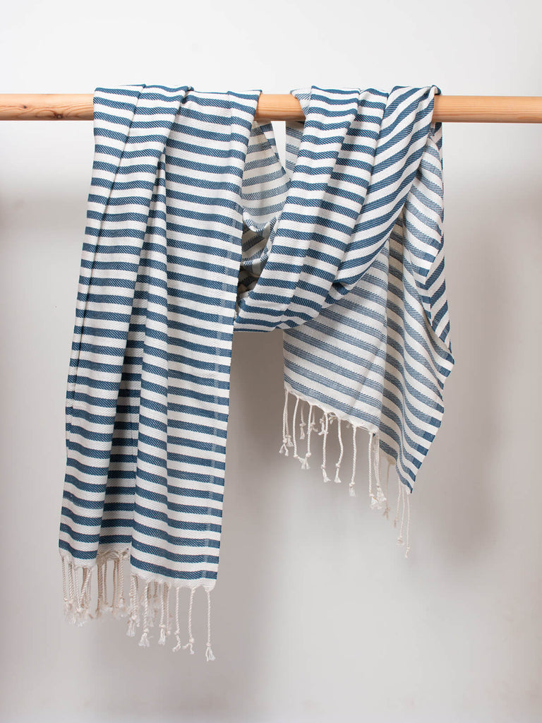Striped Sorrento Hammam Towel in indigo stripe by Bohemia DesignStriped Sorrento Hammam Towel in indigo stripe by Bohemia Design hanging from a wooden rod