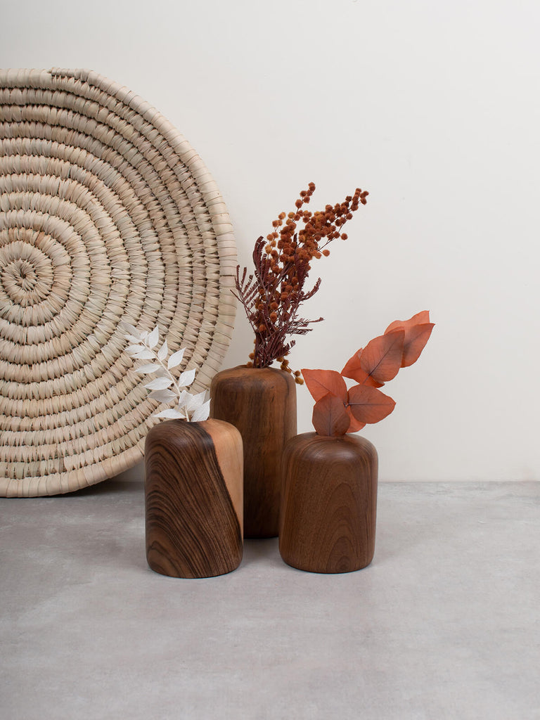 Three walnut wood mini vases by Bohemia Design with dried flower stems with palm leaf plate
