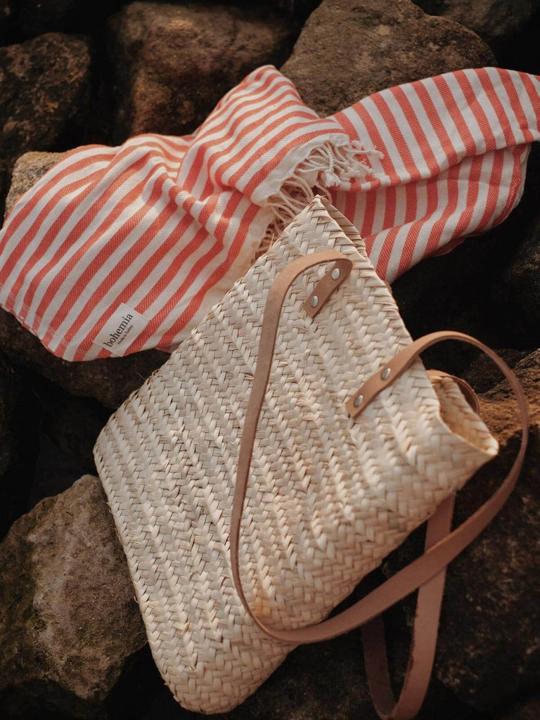 A modern tote style straw basket with long leather handles.