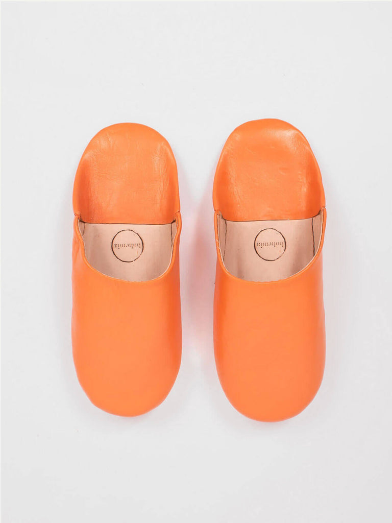 A pair of soft leather babouche slippers in a vibrant orange colour 