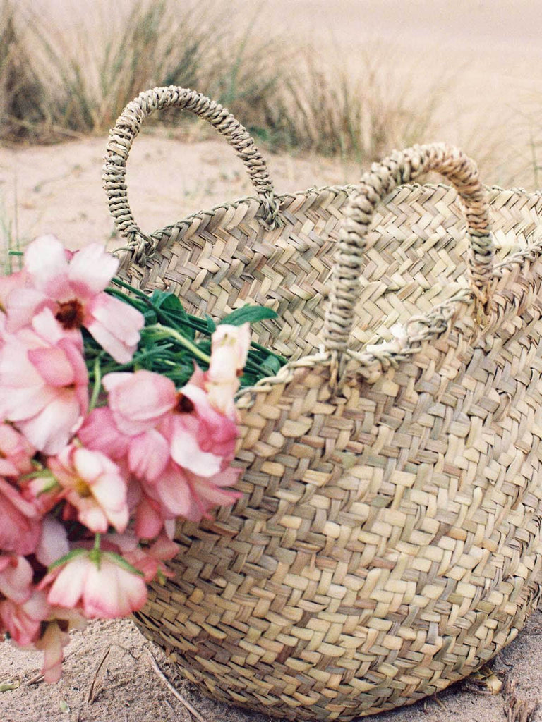 Mini Beldi Basket filled with pink flowers on a beach