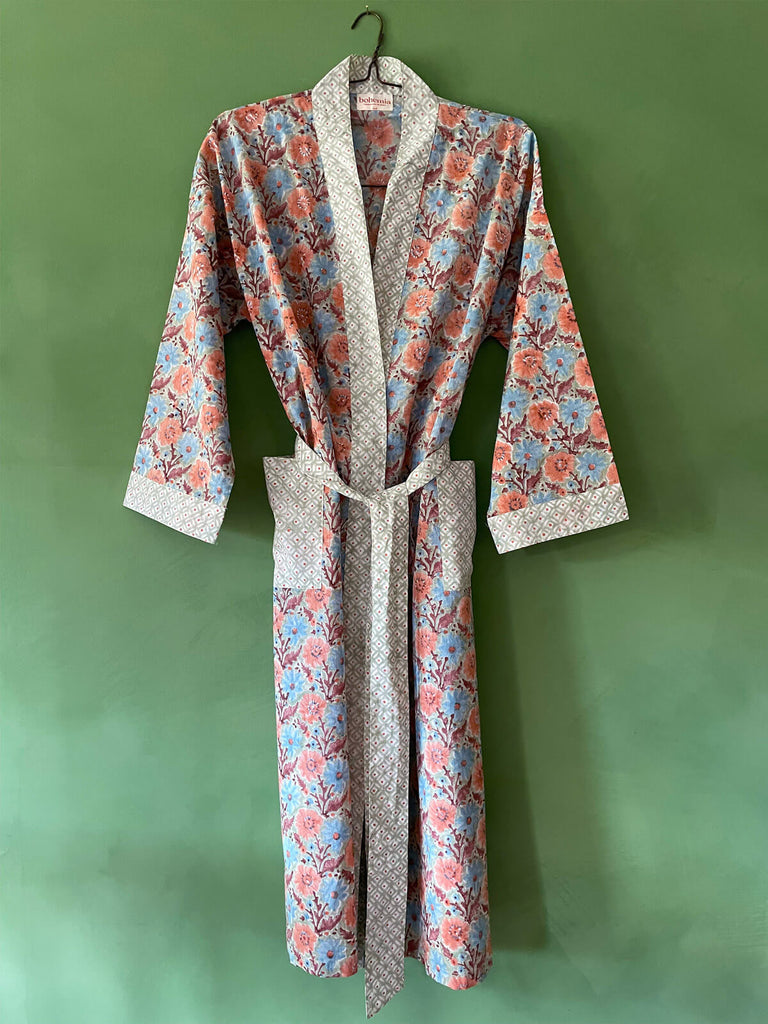 A stylish cotton robe in duck egg blue with sun-faded terracotta, pink, and dusty blue floral print, featuring pockets and a matching belt by Bohemia 