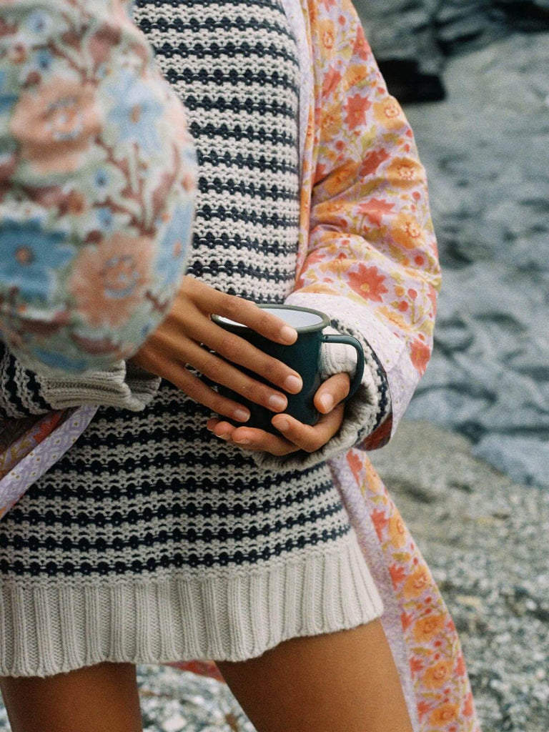 Model in a chunky knit and lilac block print robe with an enamel mug