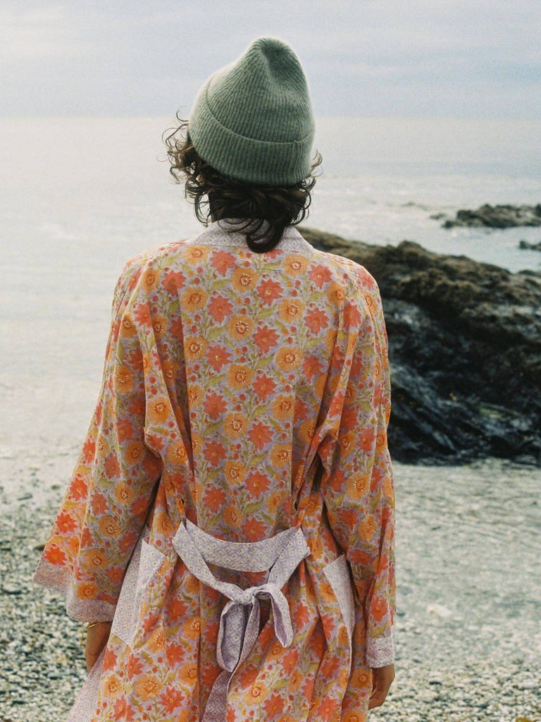 Model by the sea wearing a lilac block print robe and wool hat