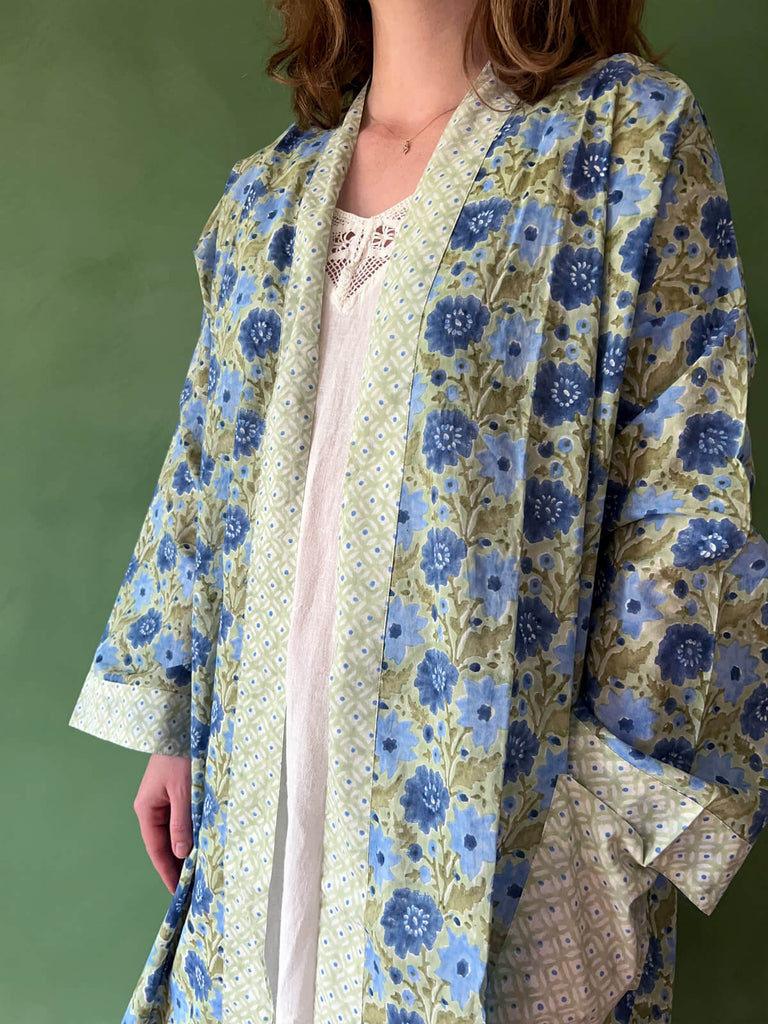 A close-up of a model wearing Bohemia floral block print cotton robe with contrasting pockets and trim in sage.