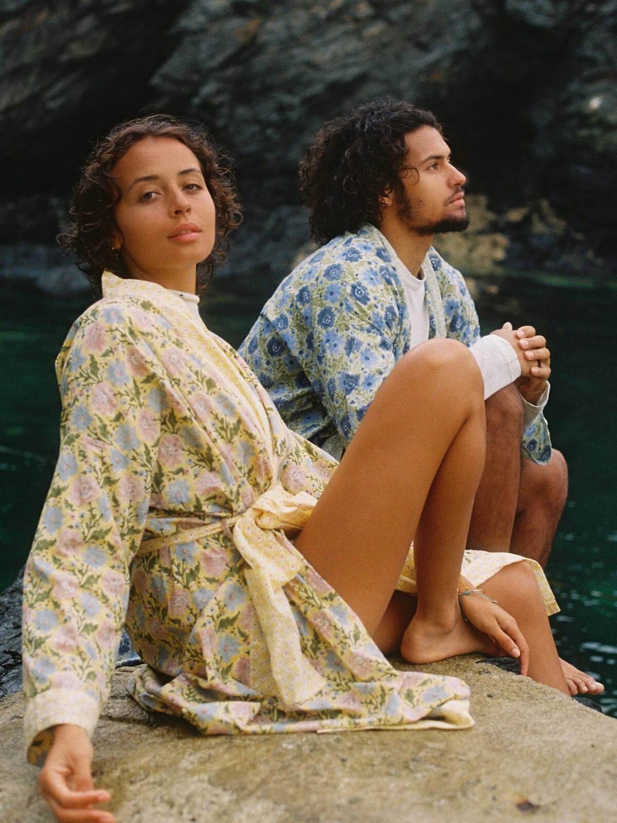 Two models wearing a buttermilk yellow and sage block print robes by the sea