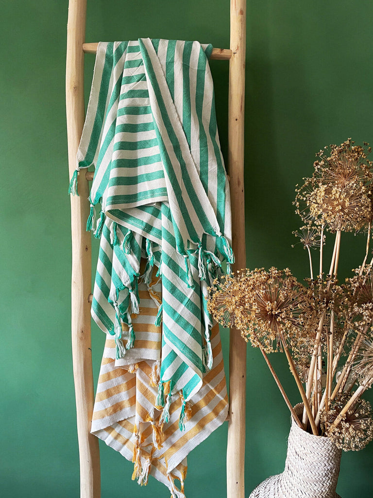 Brighton Stripe hammam towels with a wide seaside stripe and fringe, casually draped on a rustic wooden ladder | Bohemia Design