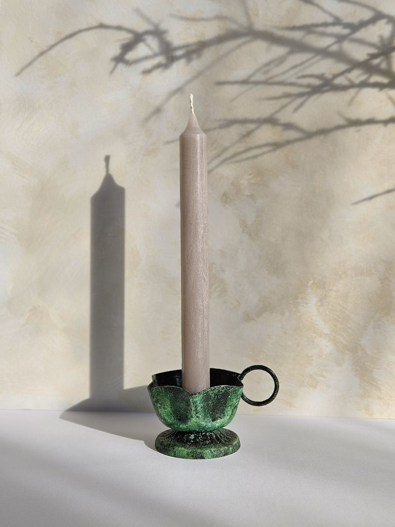 Iron candle holder in vintage moss finish with a candle on a soft, slightly textured background with natural light and subtle shadows | Bohemia