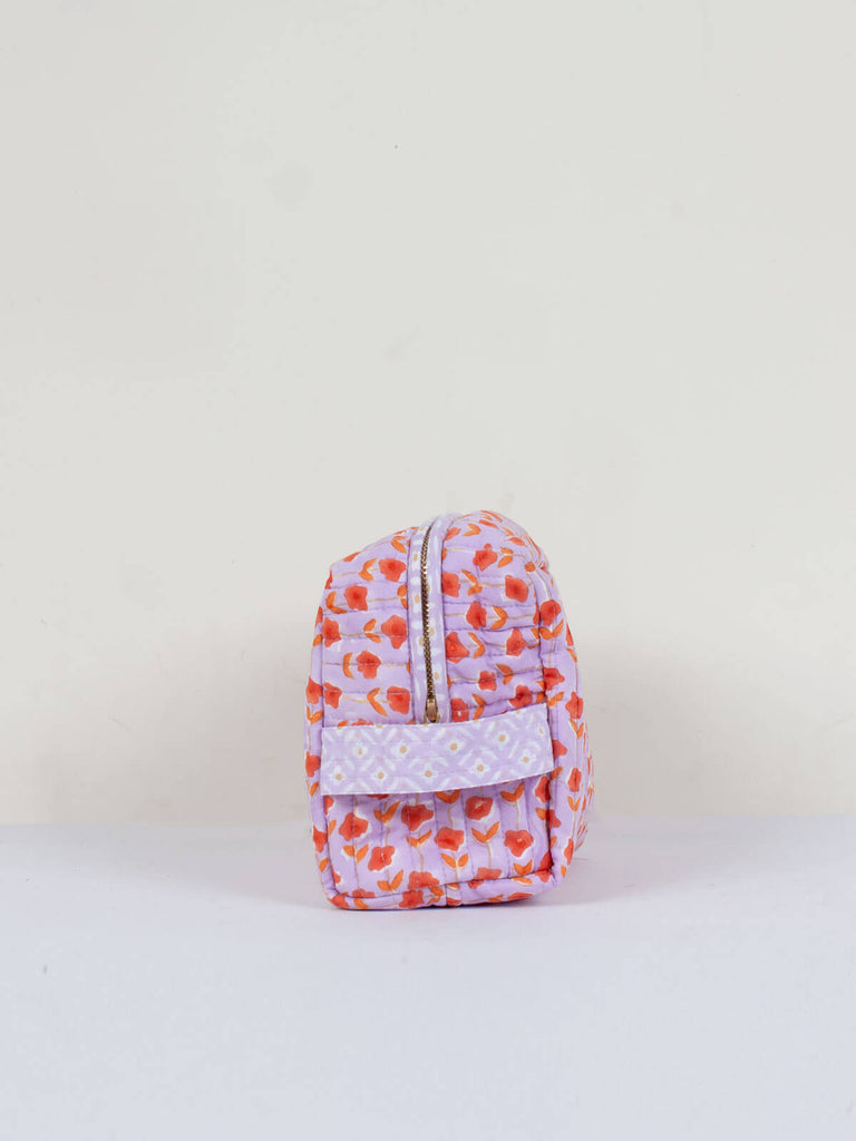 The practical carry handle on the side of a lilac and orange quilted Posie washbag