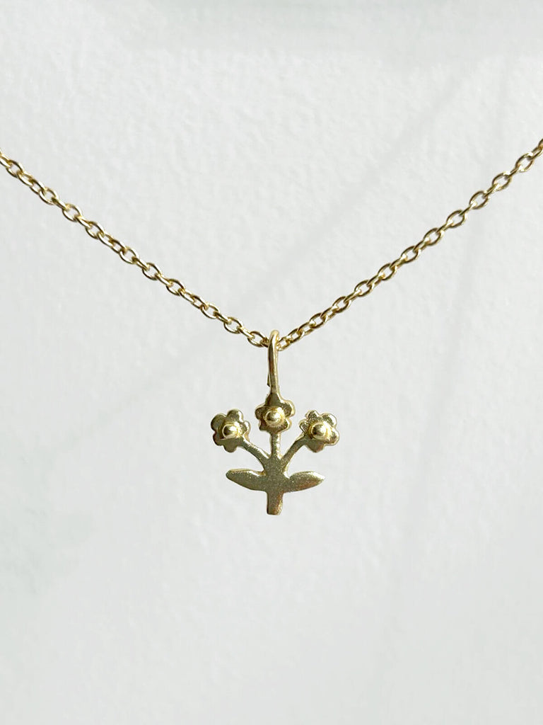 Wholesale tiny gold posie necklace featuring a minimalist flower charm