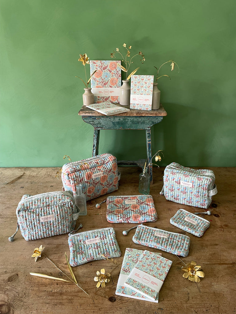 A collection of hand block-printed washbags, zip pouches, and notebooks in a soft duck egg hue in three distinctive floral pattern by Bohemia Design