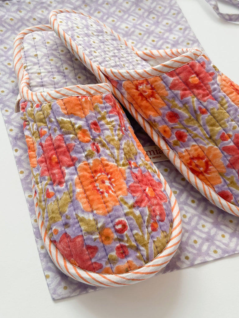 A close-up of soft cotton floral house slippers in vibrant lilac with orange, sun-faded terracotta, and warm green accents | Bohemia