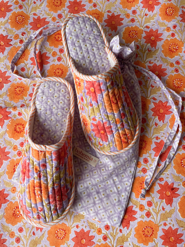 Soft and lightweight hotel slippers with a ditsy print drawstring bag shown on a matching floral background, Lilac | Bohemia Design