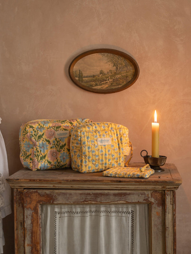Buttermilk yellow washbags of different sizes on an antique dresser with lit candle