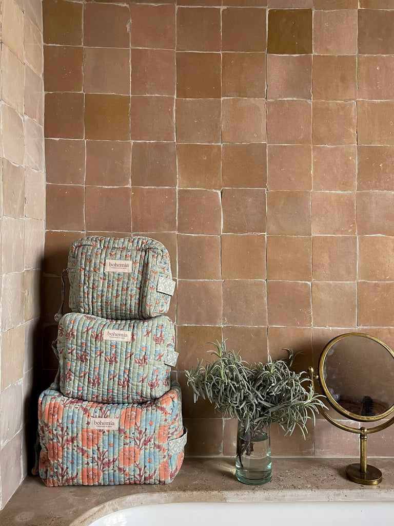 Three hand block printed washbags in soft duck egg set in a Moroccan neutral-toned bathroom with square artisanal tiles by BohemiaDesign