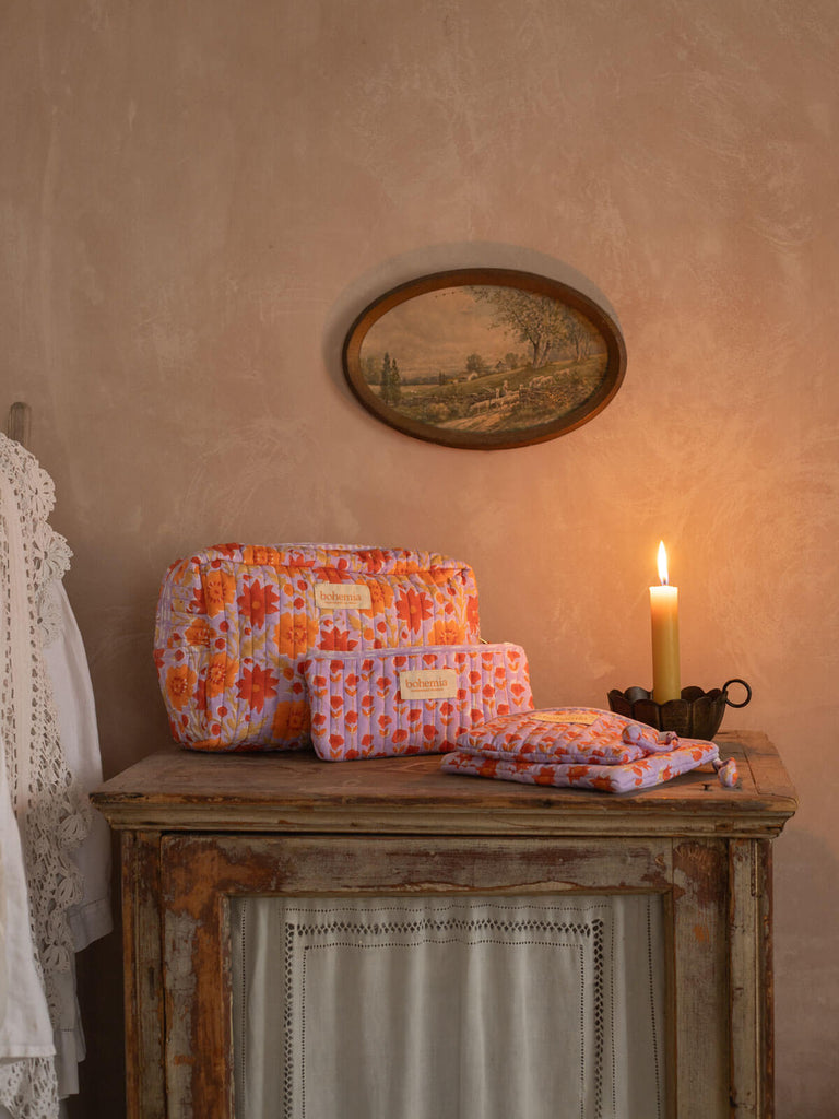 Vintage pink washbags of different sizes on an antique dresser with lit candle