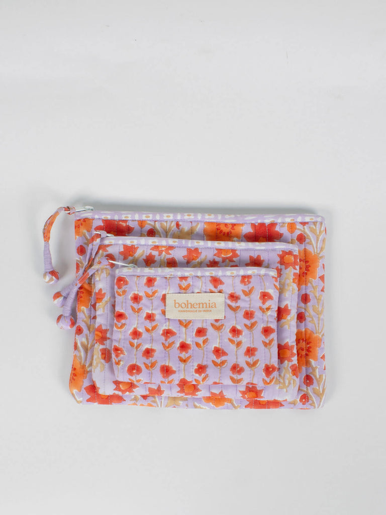 Group of quilted zip pouches with a lilac and orange floral block printed pattern