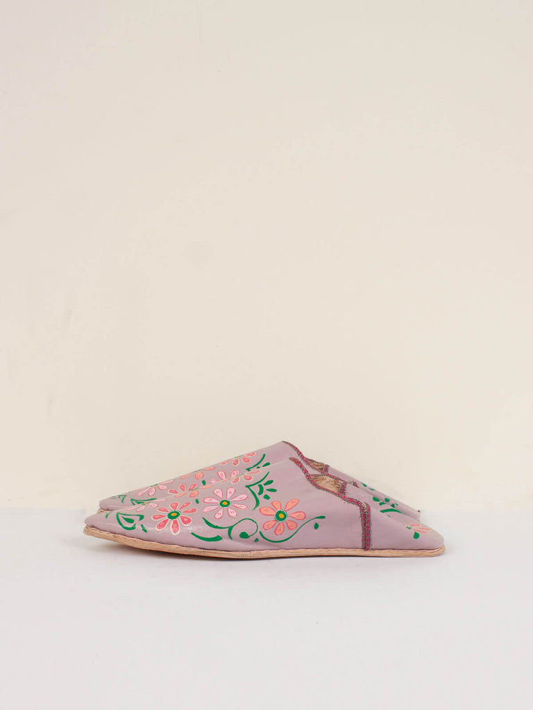 Side view of a pair of pointed babouche slippers dusky lilac leather with hand painted floral pattern