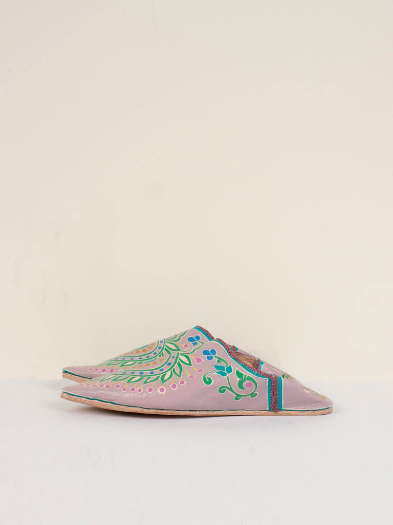 Side view a pair of exquisitely painted pointed babouche slippers In a dusky lilac leather