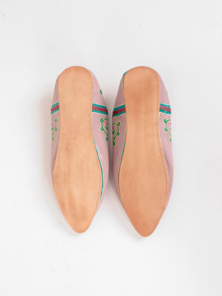 The firm leather soles of a pair ofhand painted pointed babouche slippers in a dusky lilac leather