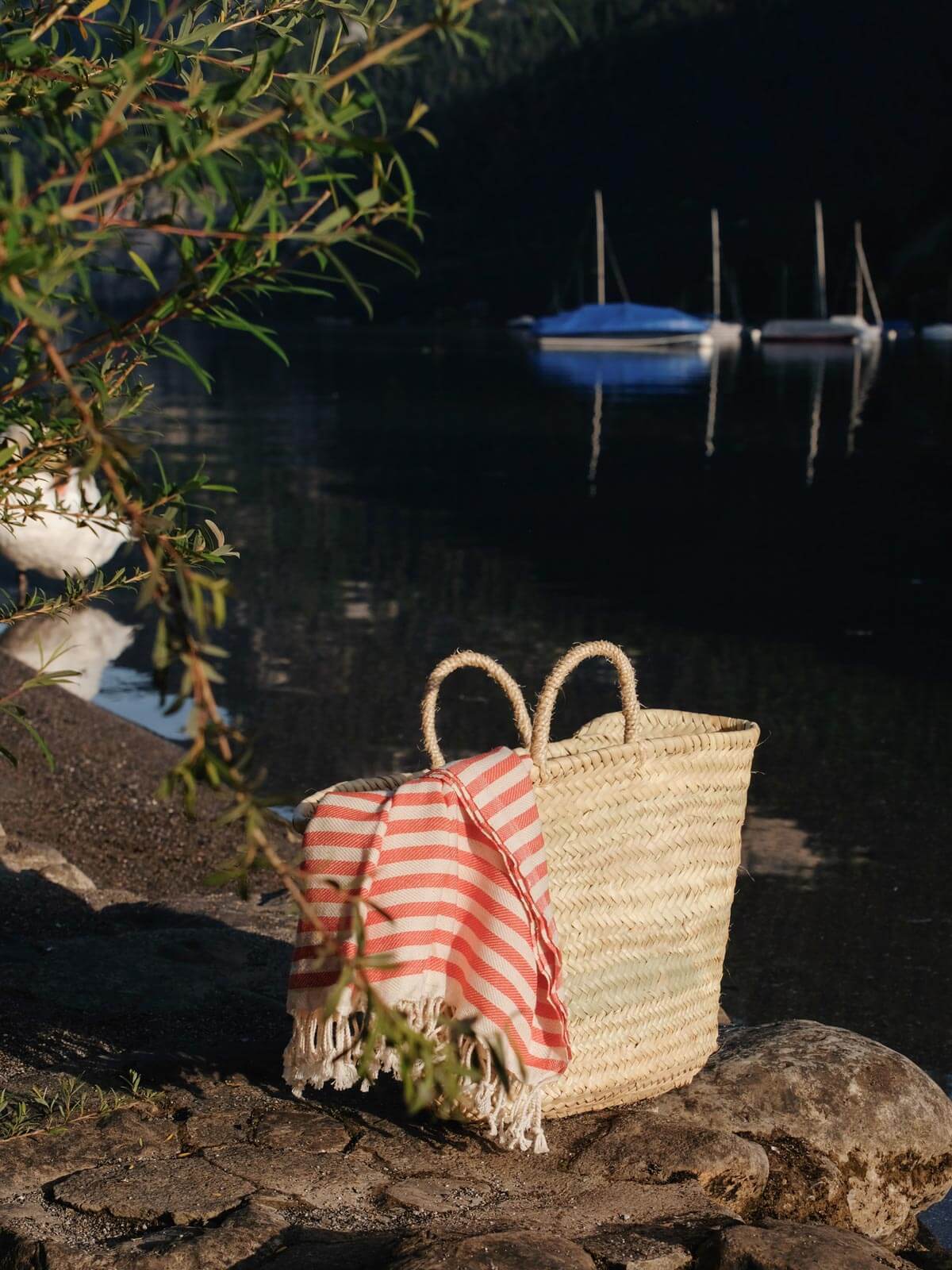 A classic French style Market Basket on a river bank with boats in the background