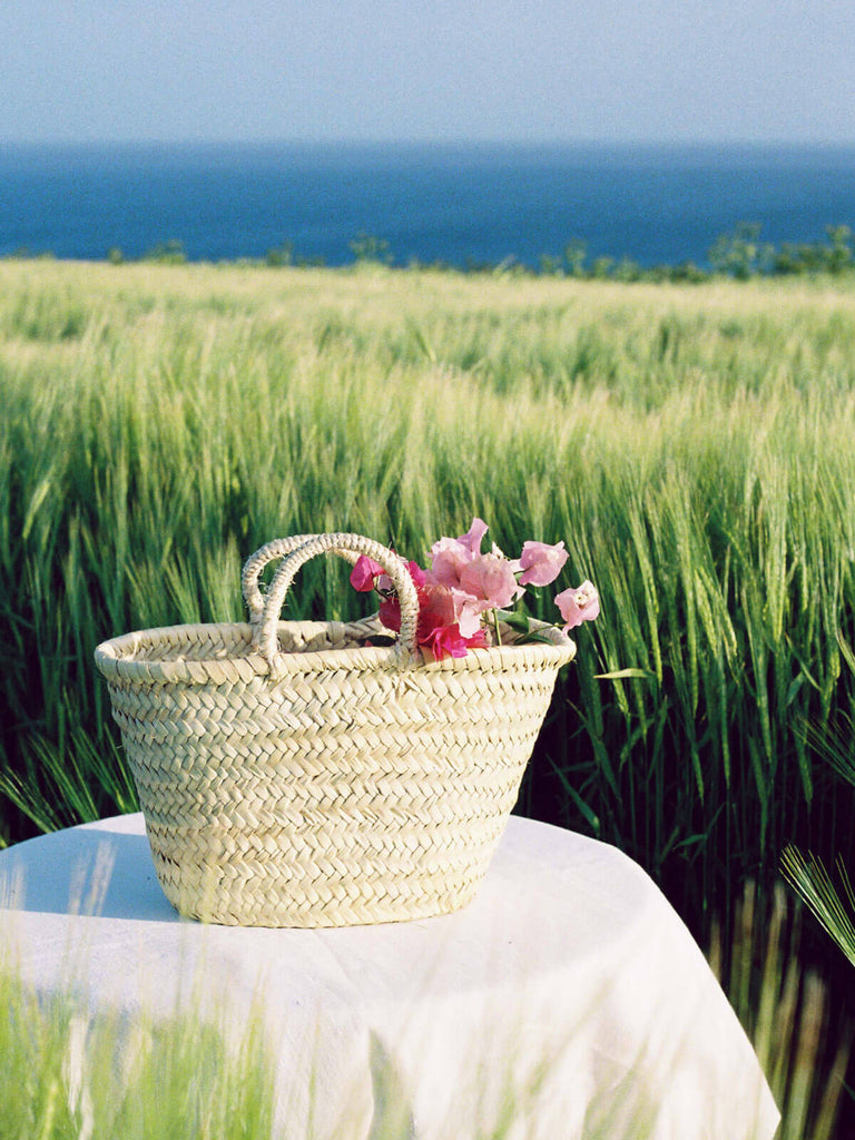 A small Market Basket filled with flowers by the sea