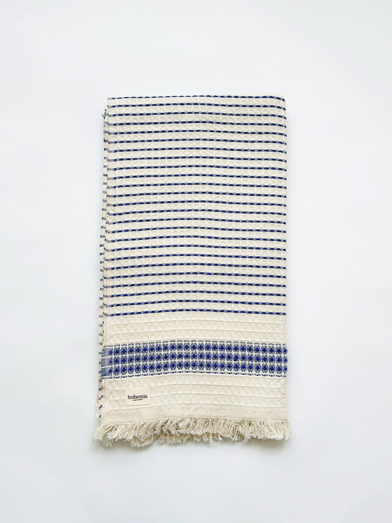 Beautifully tactile Turkich cotton hammam towel with a subtle blue stripe and hand-tied tassel fringe, featuring a waffle texture weave | Bohemia Design