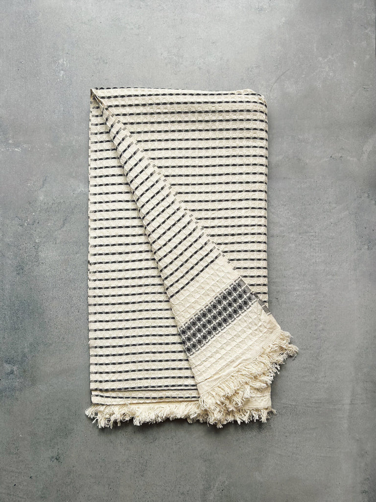 Milos Check Hammam Towel with a fine waffle textured weave and a charcoal stripe, revealing soft cotton fabric on both sides | Bohemia Design