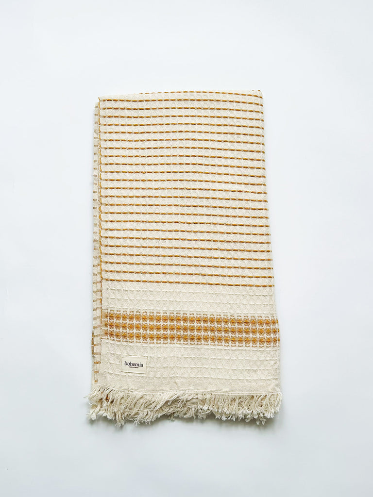 Beautifully tactile, waffle textured Milos Check Hammam Towel with a subtle mustard yellow striped pattern and finished with hand-tied tassel fringe | Bohemia Design