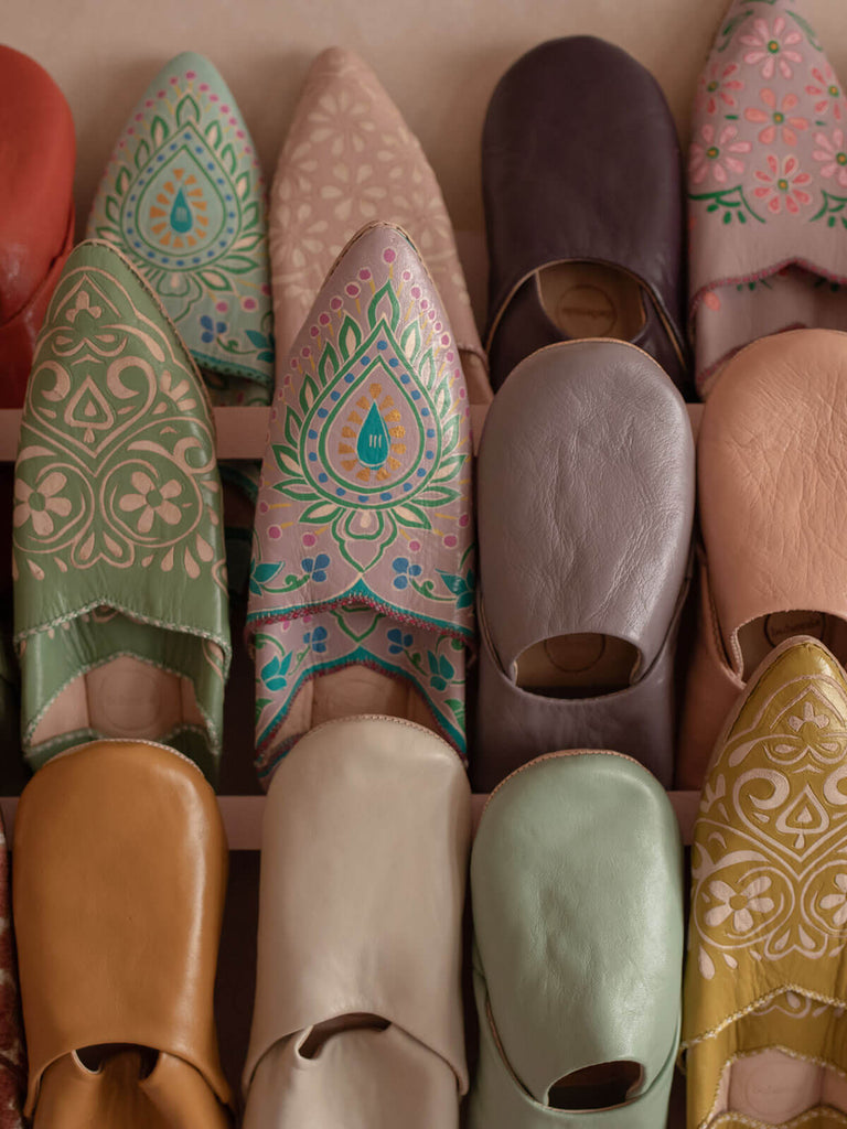 A display of various styles of Bohemia Moroccan babouche slippers including handpainted designs