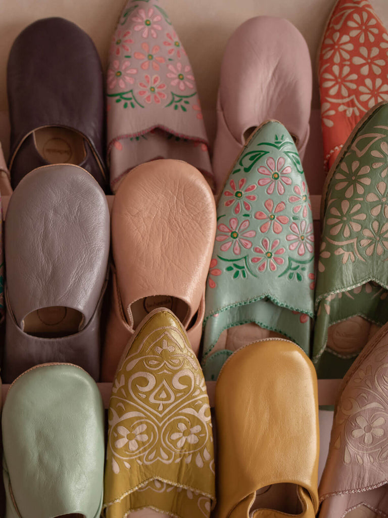 A display of various styles of Bohemia Moroccan babouche slippers including hand painted designs