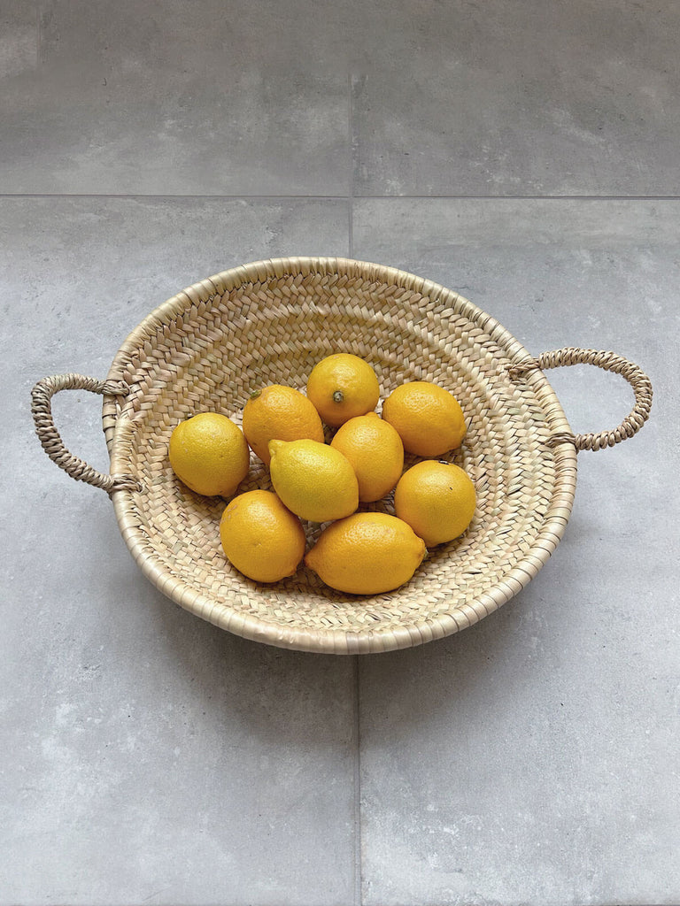 A small woven plate used as a fruit platter with lemons