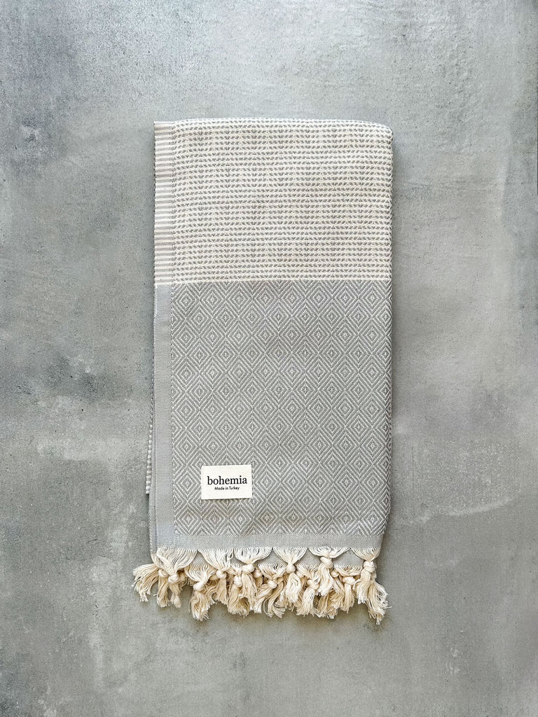 Soft cotton Nordic Dot Hammam Towel in pearl grey diamond pattern on a grey textured background by Bohemia Design