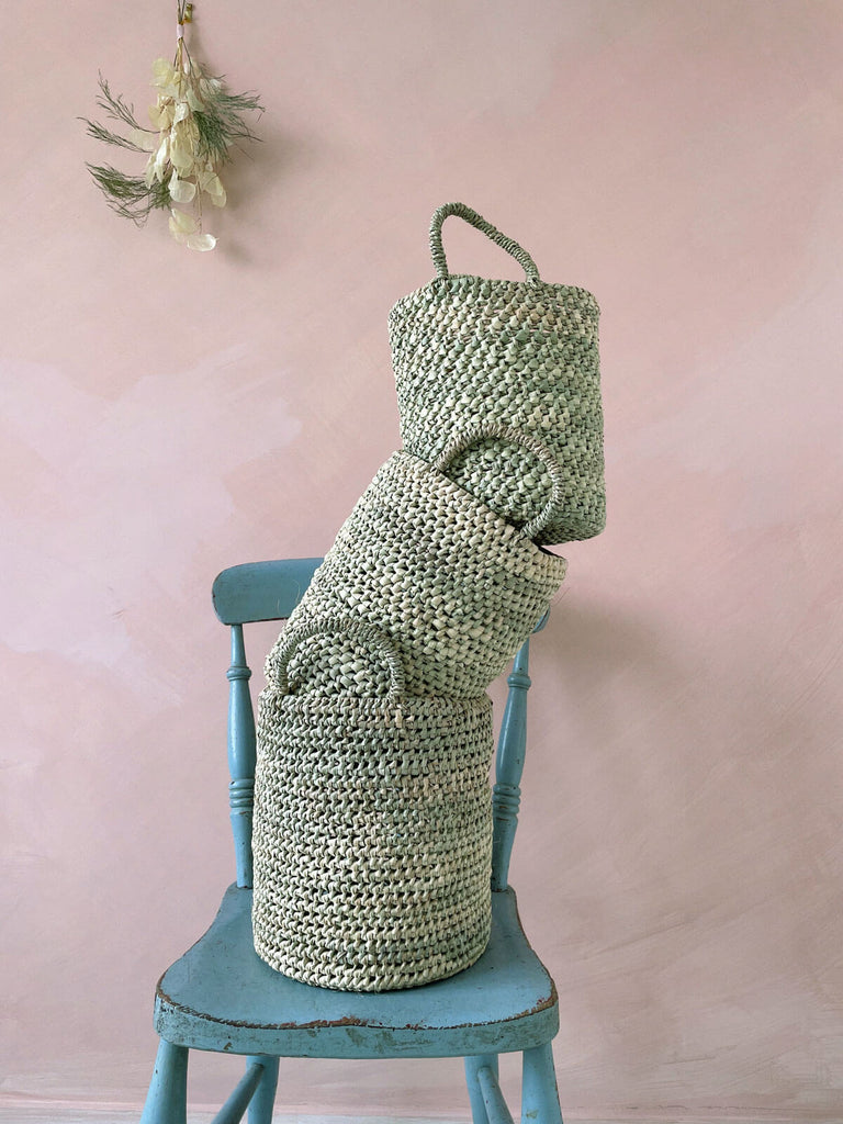 Three different sized round nesting baskets stacked on a blue chair