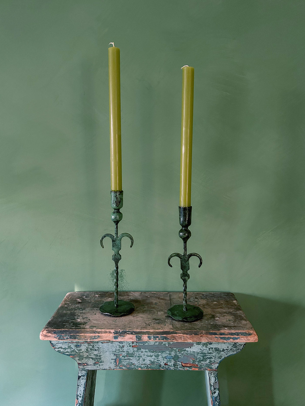 A pair of artisanal candle holders with a unique palm tree design and vintage verdigris patina, paired with two candles | Bohemia