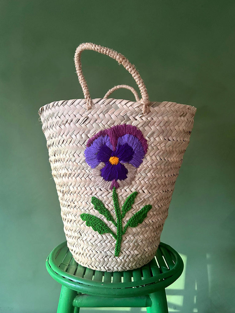 A close-up view of a hand-embroidered pansy flower, intricately stitched onto a bucket-shaped basket | Bohemia Design Wholesale