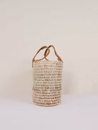 Side view showing the unique oval shape of the natural woven basket with mustard pleated leather handles