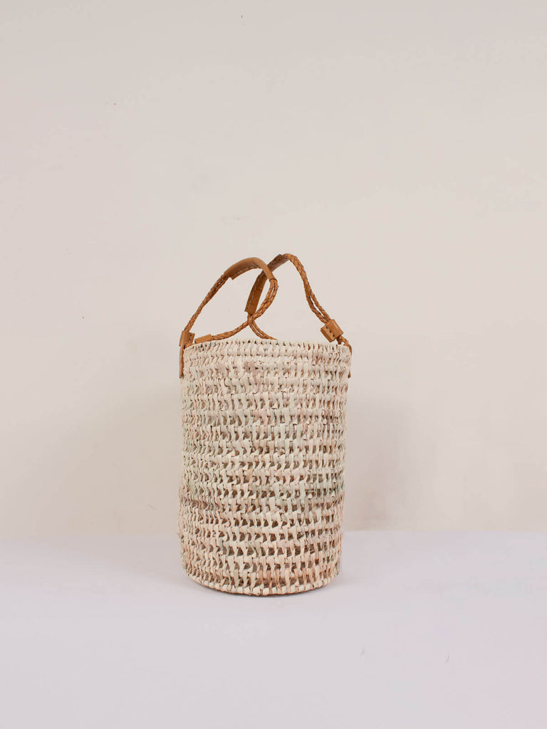 Side view showing the unique oval shape of the natural woven basket with mustard pleated leather handles