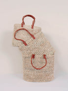 Set of 3 different sized open weave baskets in a unique oval shape with pleated leather handles in warm terracotta.