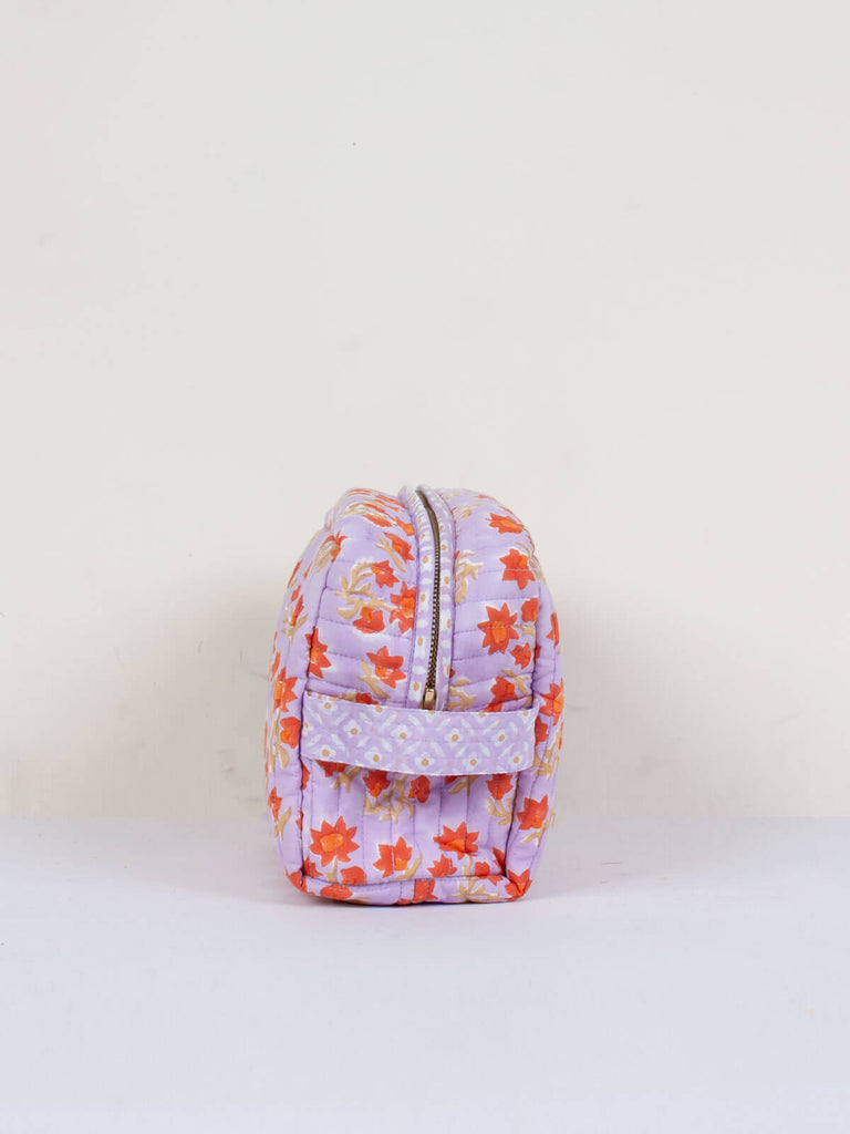 The practical carry handle on the side of a lilac quilted Posie washbag